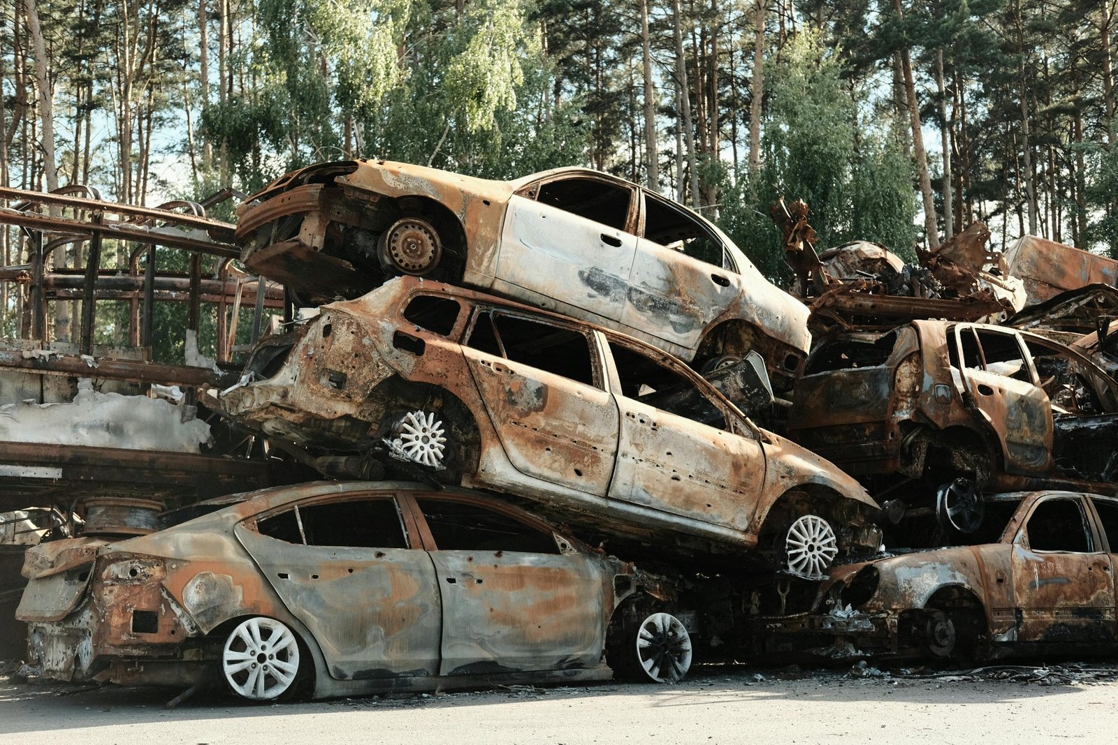 Gestión Dispersiones Mendoza Viladecans - Pile of rusty destroyed cars in outdoor junkyard surrounded by trees.