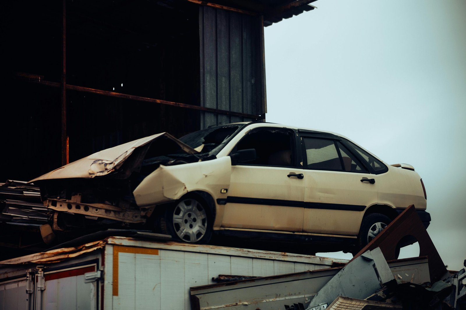 Gestión Dispersiones Mendoza Viladecans - A damaged car sits atop a metal scrap heap, showing a scene of automotive decay.